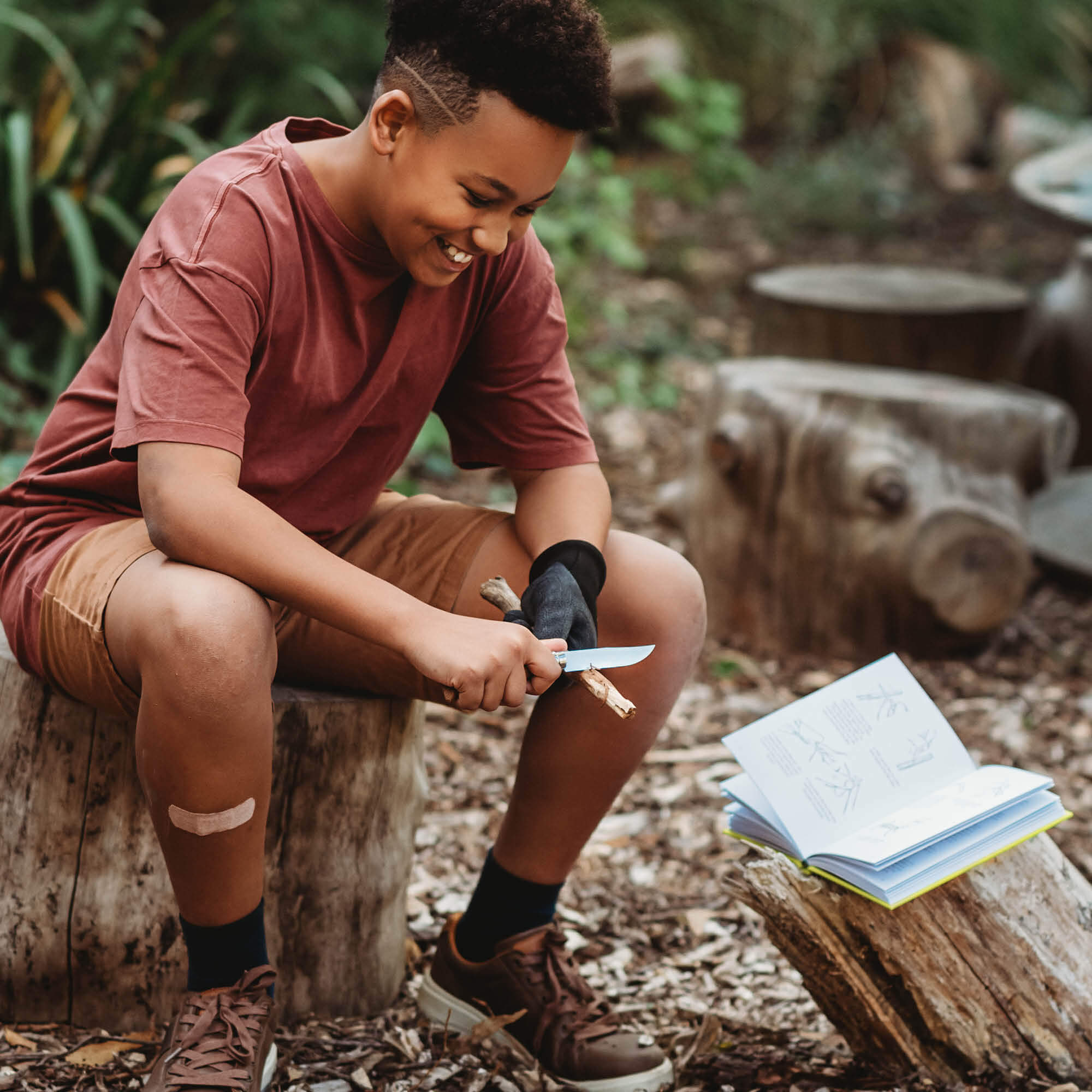 Boy doing wood whittling in the forest, using 50 Things to do with a Penknife book by Matt Collins with advanced No08 wood whittling knife by Opinel, sold by Your Wild Books in a bundle for 13% off