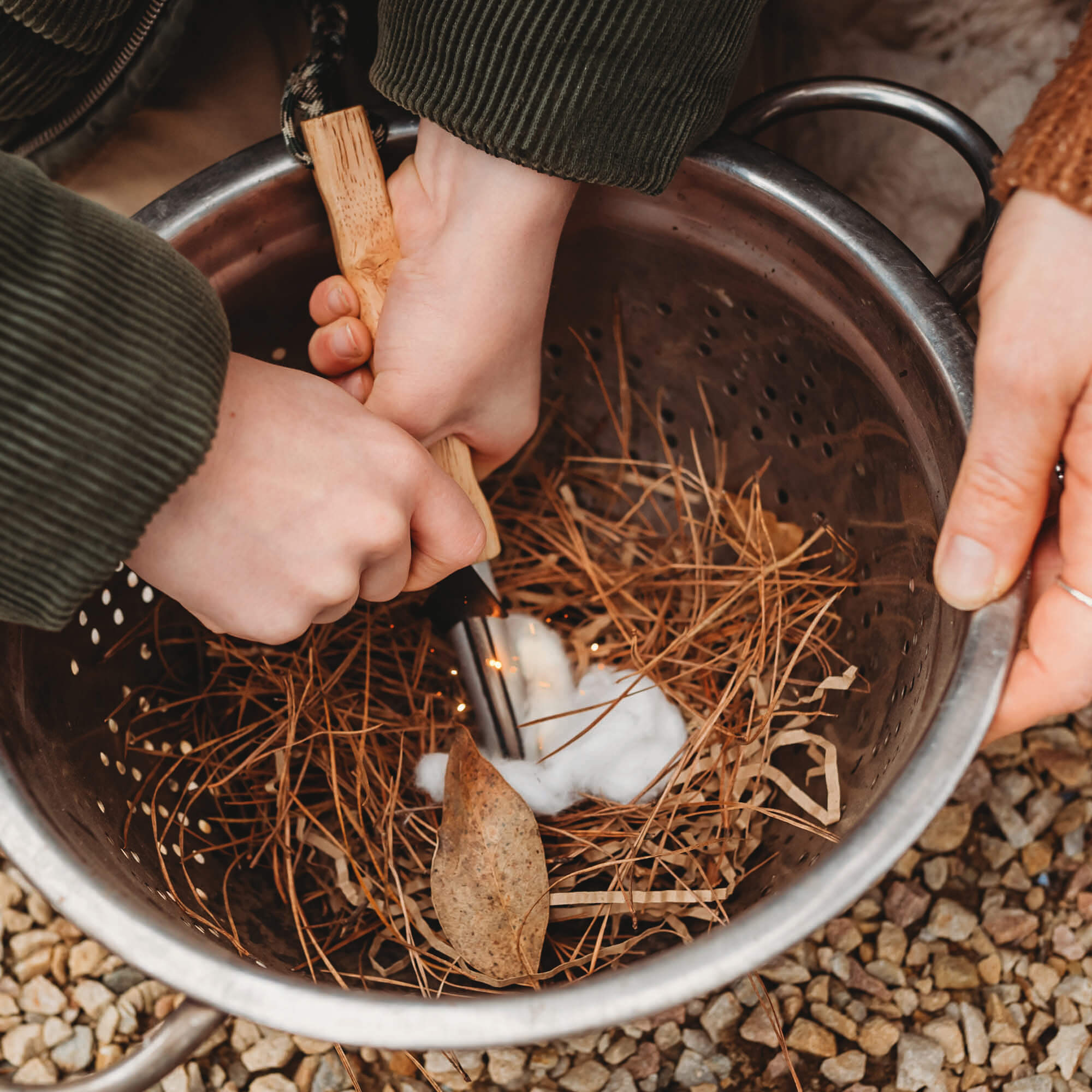 Boy using flint and stone style fire starter with wooden handle with kindling made by Your Wild Books