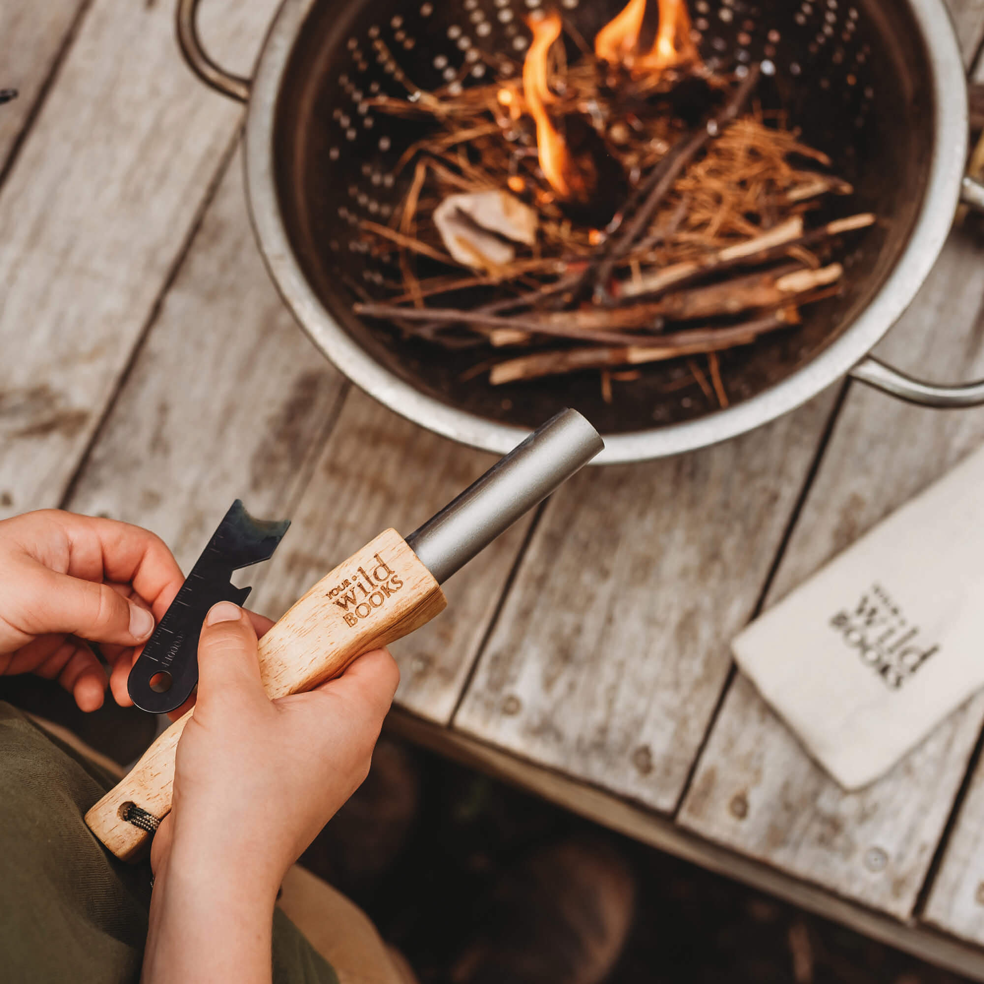 Boy using flint and stone style fire starter with wooden handle with kindling made by Your Wild Books