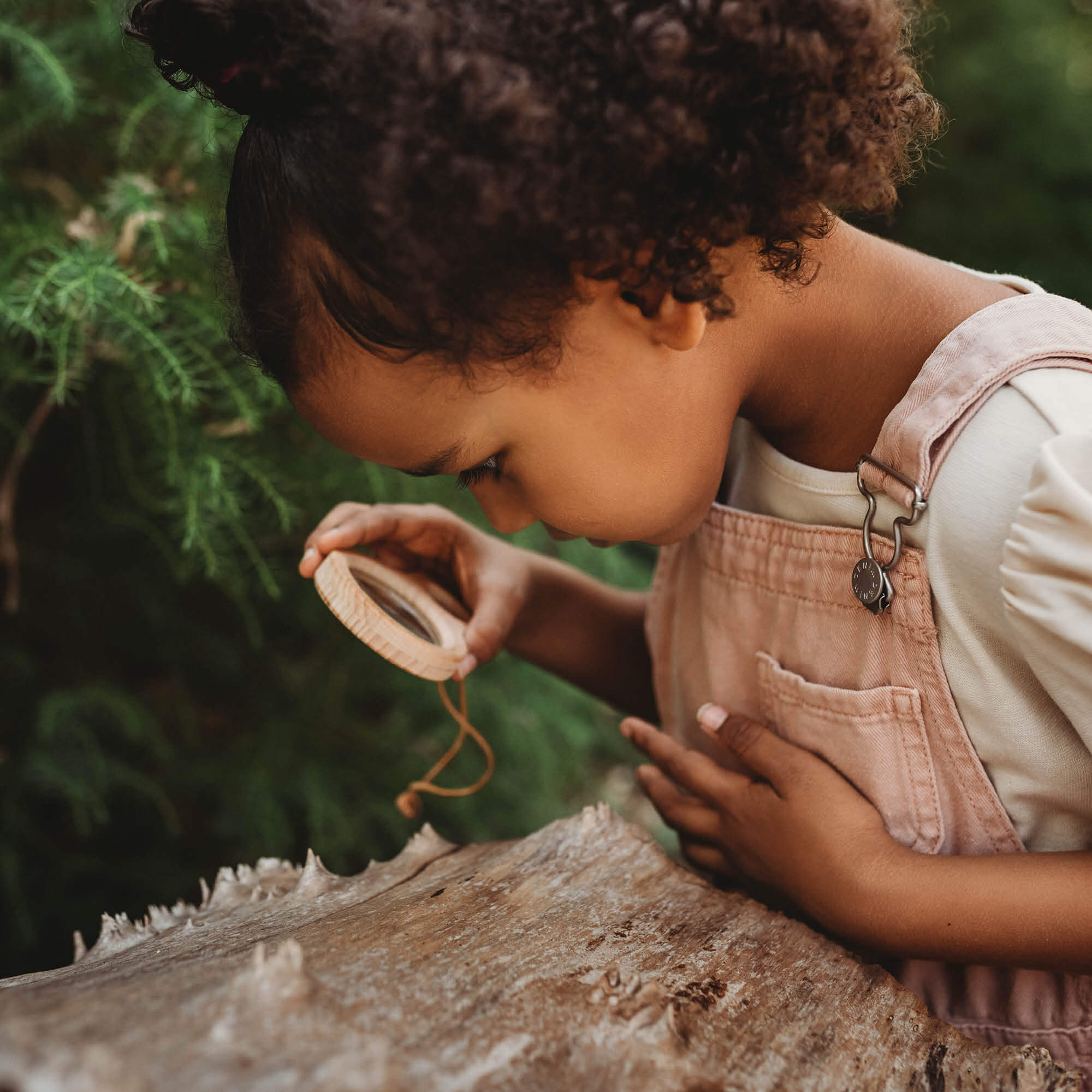 Girl holding Kikkerland dual magnifier wooden magnifying glass with two lenses for exploring nature and play from Your Wild Books