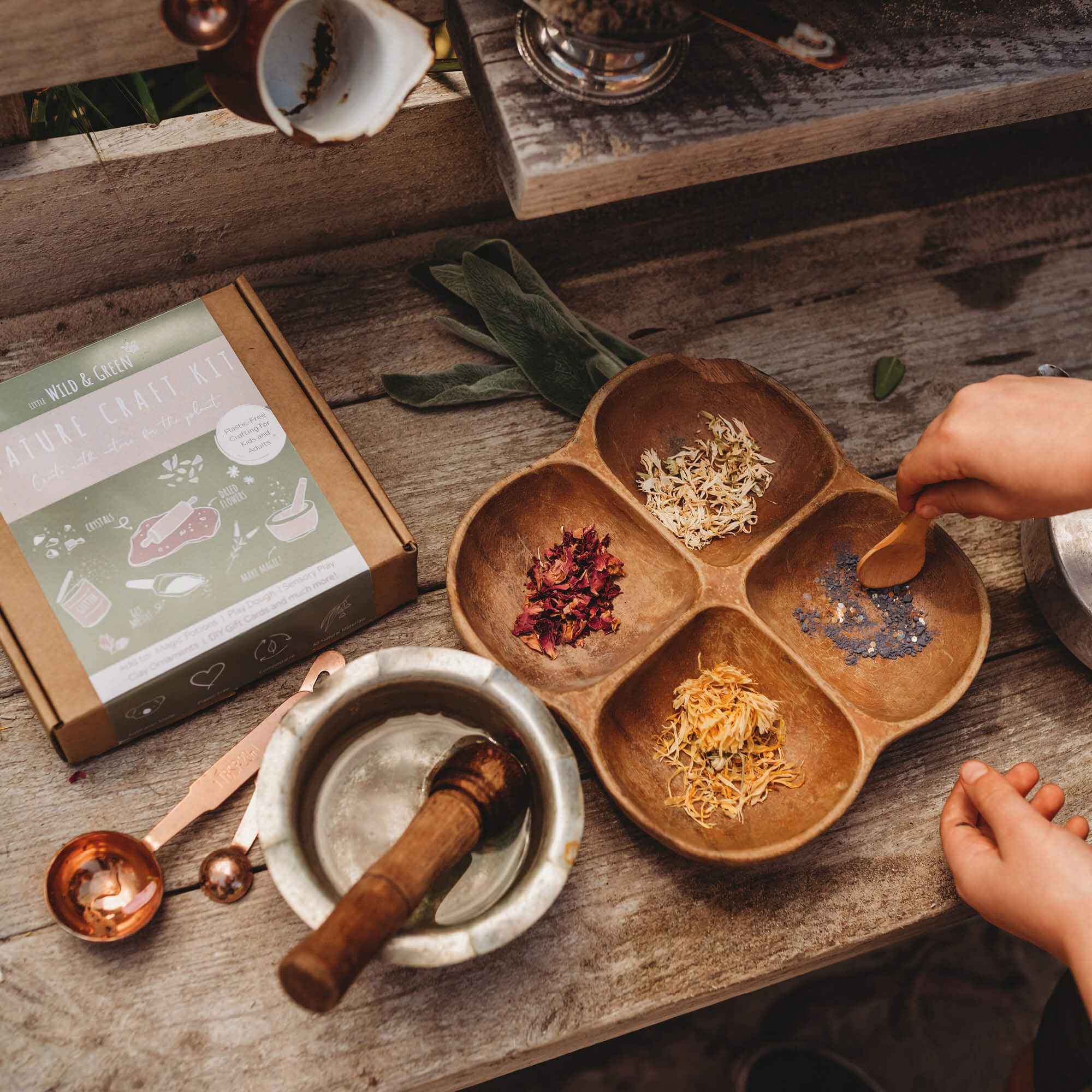 Nature craft kit by Little Wild and Green made with all natural materials including 4 bags of petals, 2 paint powders, 1 eco glitter, a box of crystal chips and a wooden spoon. perfect for nature crafting for kids including playdough, clay and magic potions from Your Wild Books