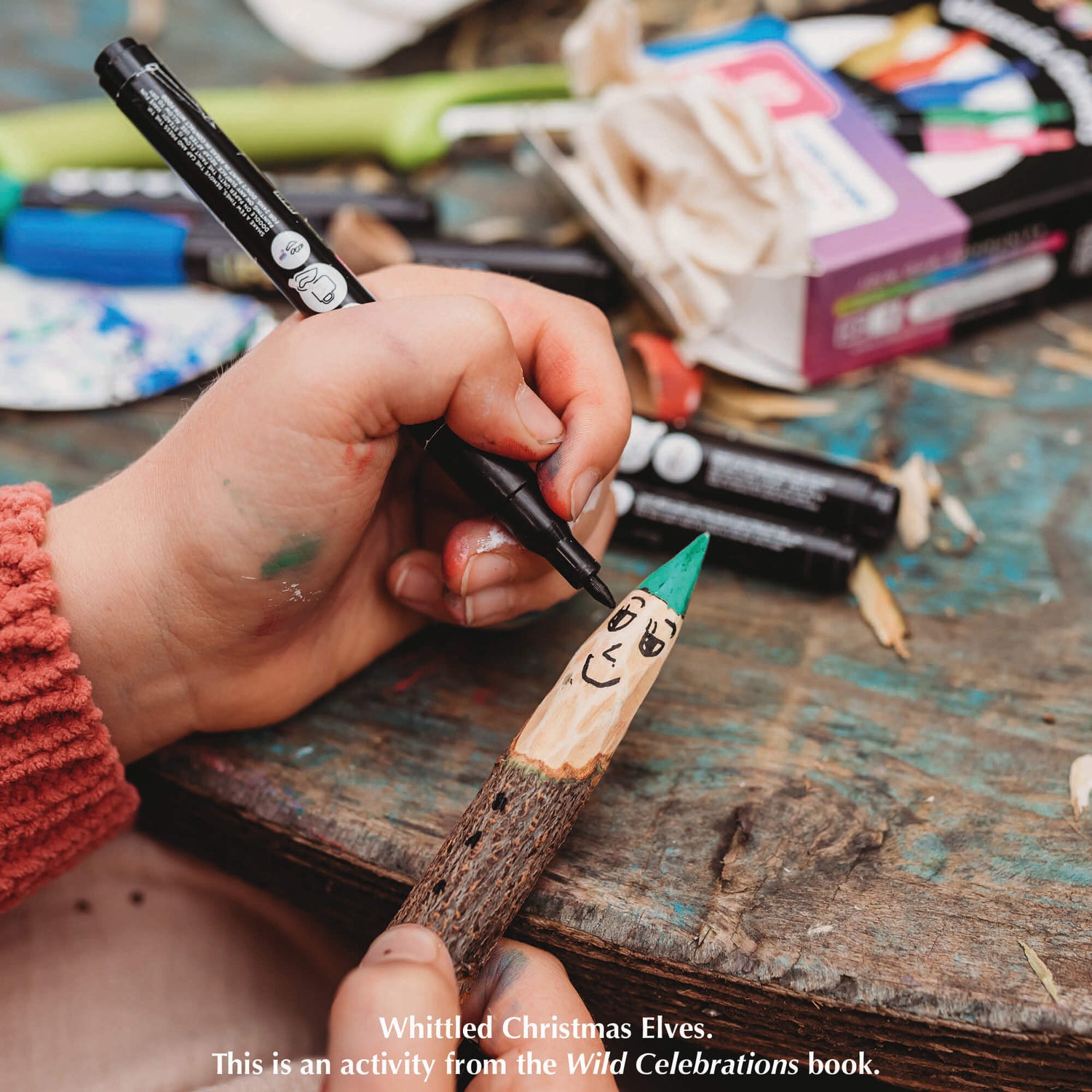 Girl making a whittled stick person, a nature craft activity from Your Wild Books that have been decorated with paint pens from Life of Colour