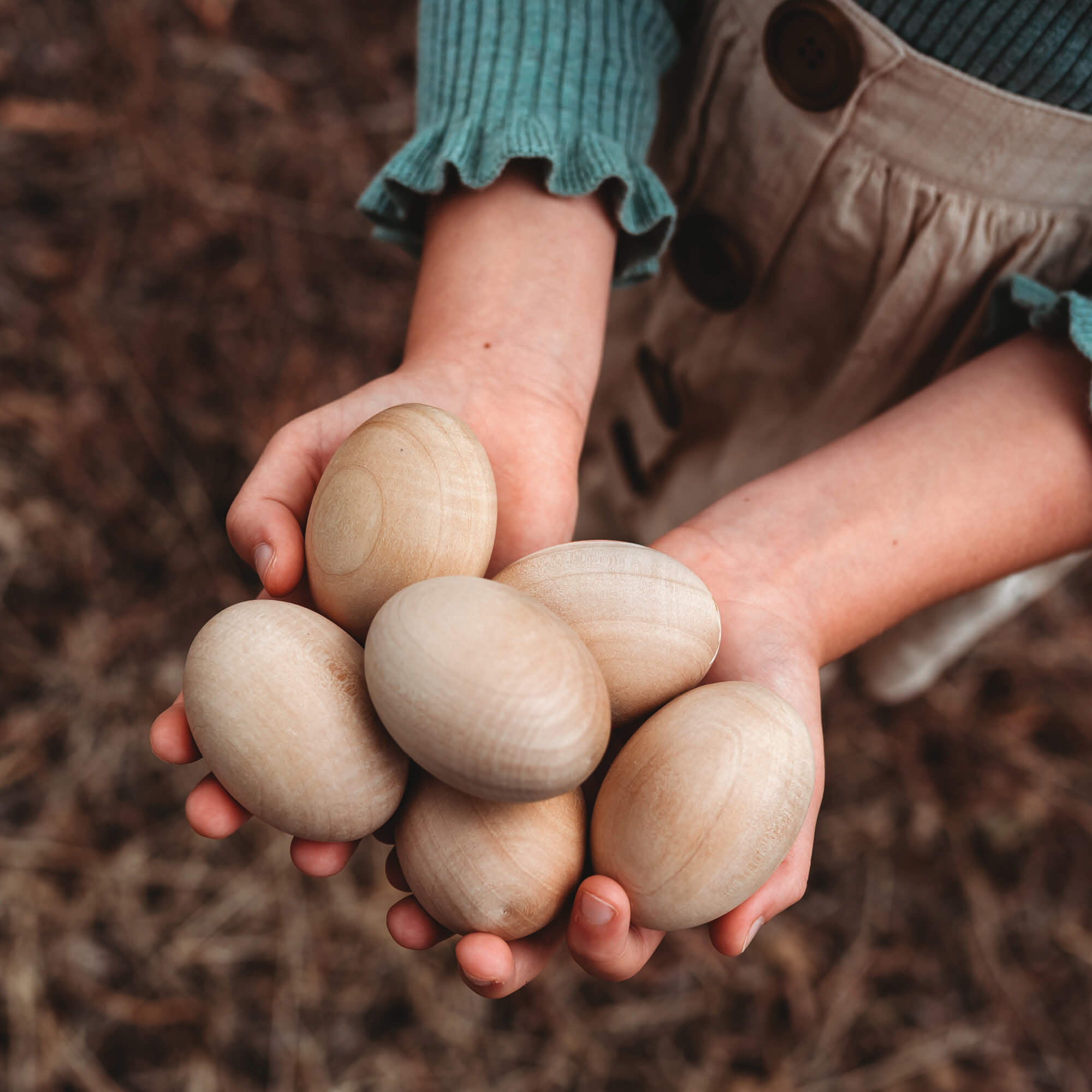 Girl holding 6 large wooden eggs for craft sugar free alternative to Easter eggs Easter craft made by Your Wild Books
