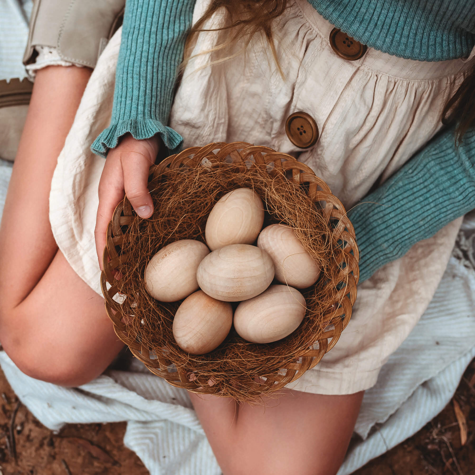 Girl holding a basket of large wooden eggs for craft sugar free alternative to Easter eggs Easter craft made by Your Wild Books