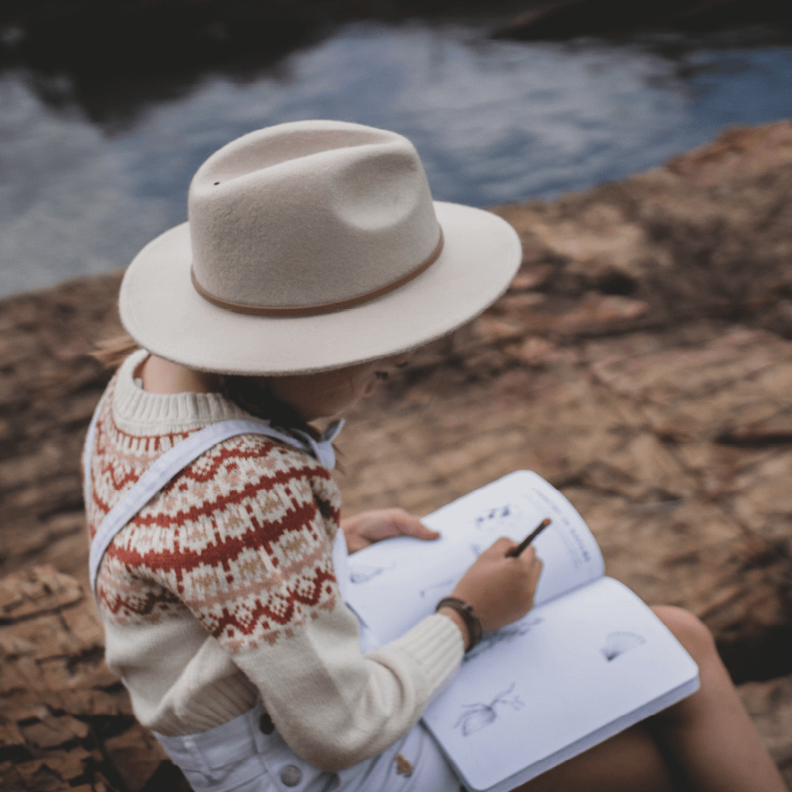 Girl in nature doing activity from Your Wild Activity Book, nature inspired games and puzzles, made in Australia by Your Wild Books.