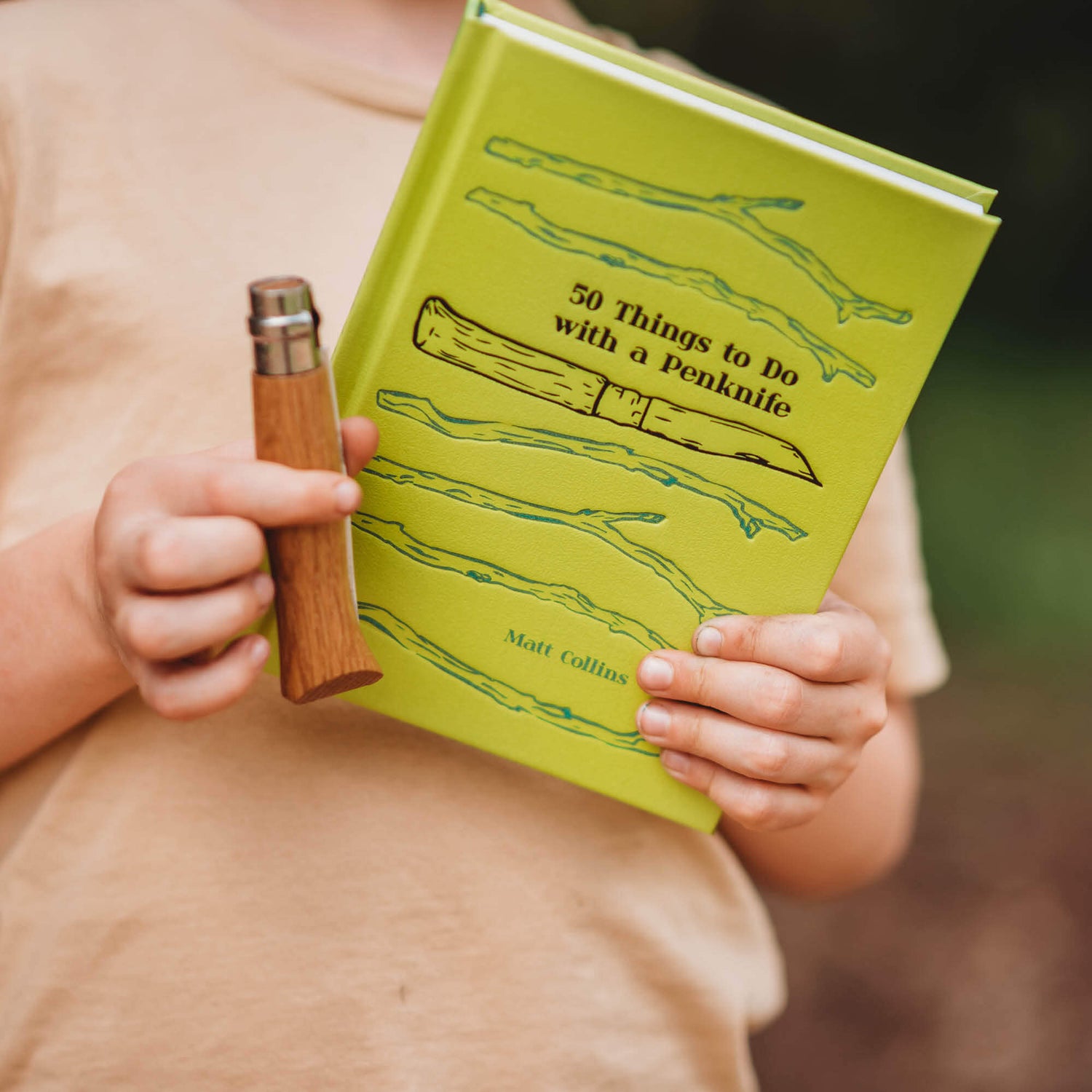 Boy holding 50 Things to do with a Penknife book by Matt Collins with advanced No08 wood whittling knife by Opinel, sold by Your Wild Books in a bundle for 13% off