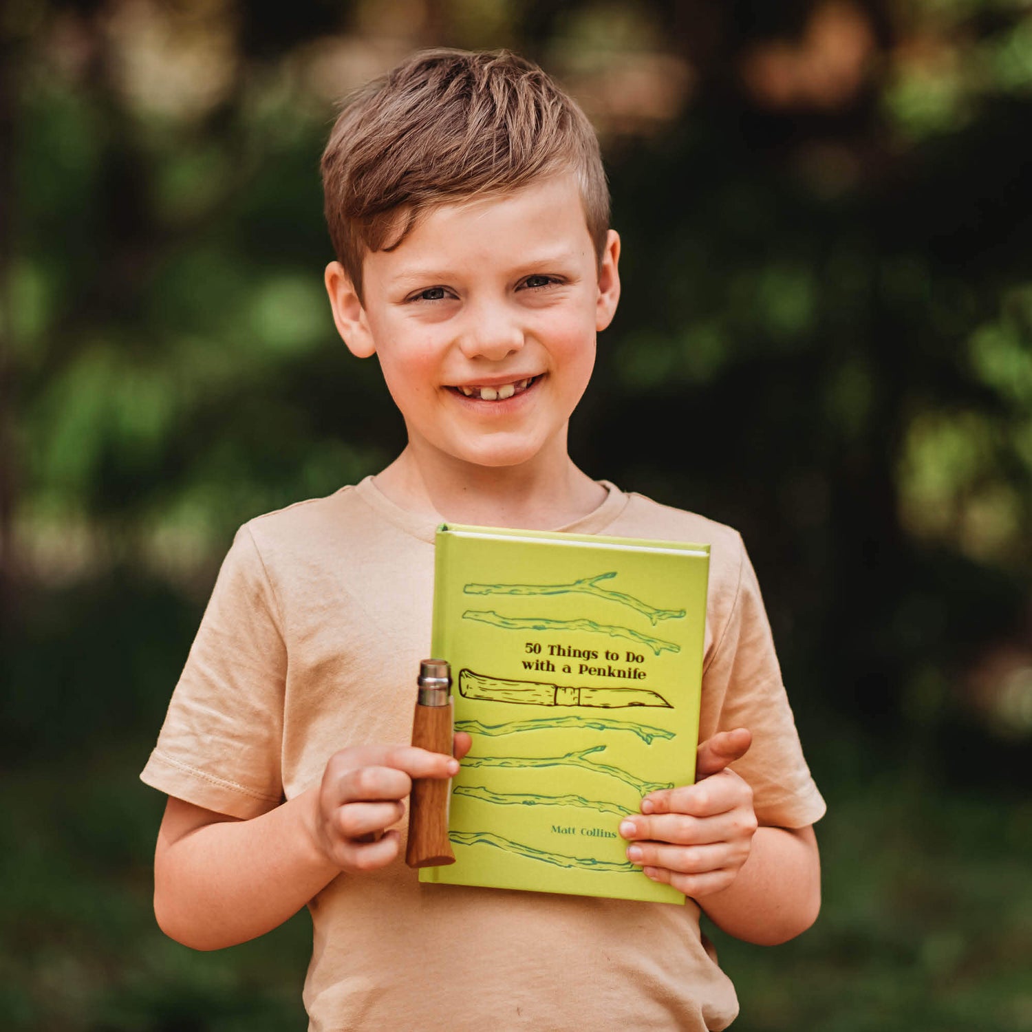 Boy in nature holding 50 things to do with a penknife book wood whittling book for kids wood working projects from Your Wild Books
