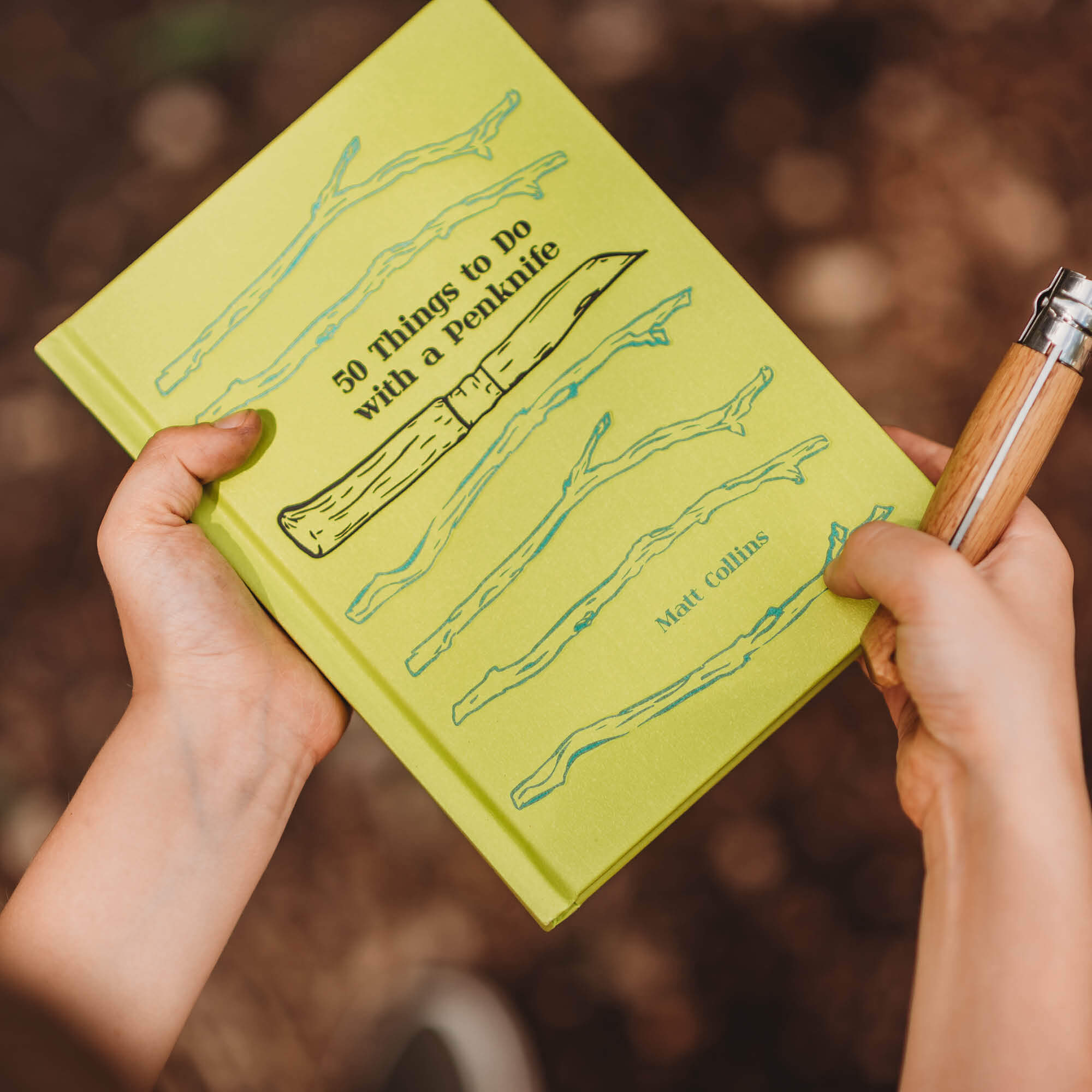 Child holding 50 things to do with a penknife book wood whittling book for kids wood working projects from Your Wild Books