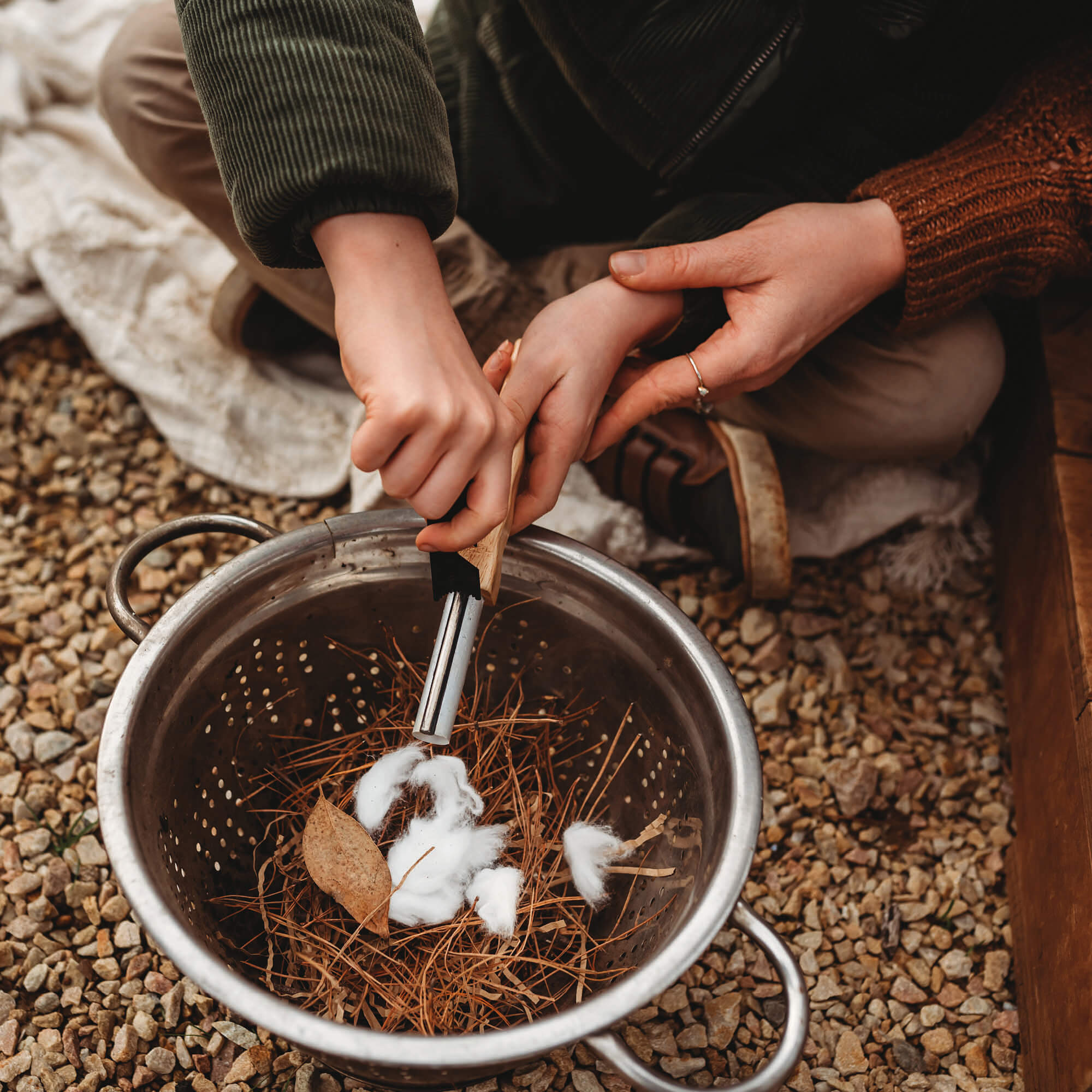 Boy using flint and stone style fire starter with wooden handle with kindling made by Your Wild Books