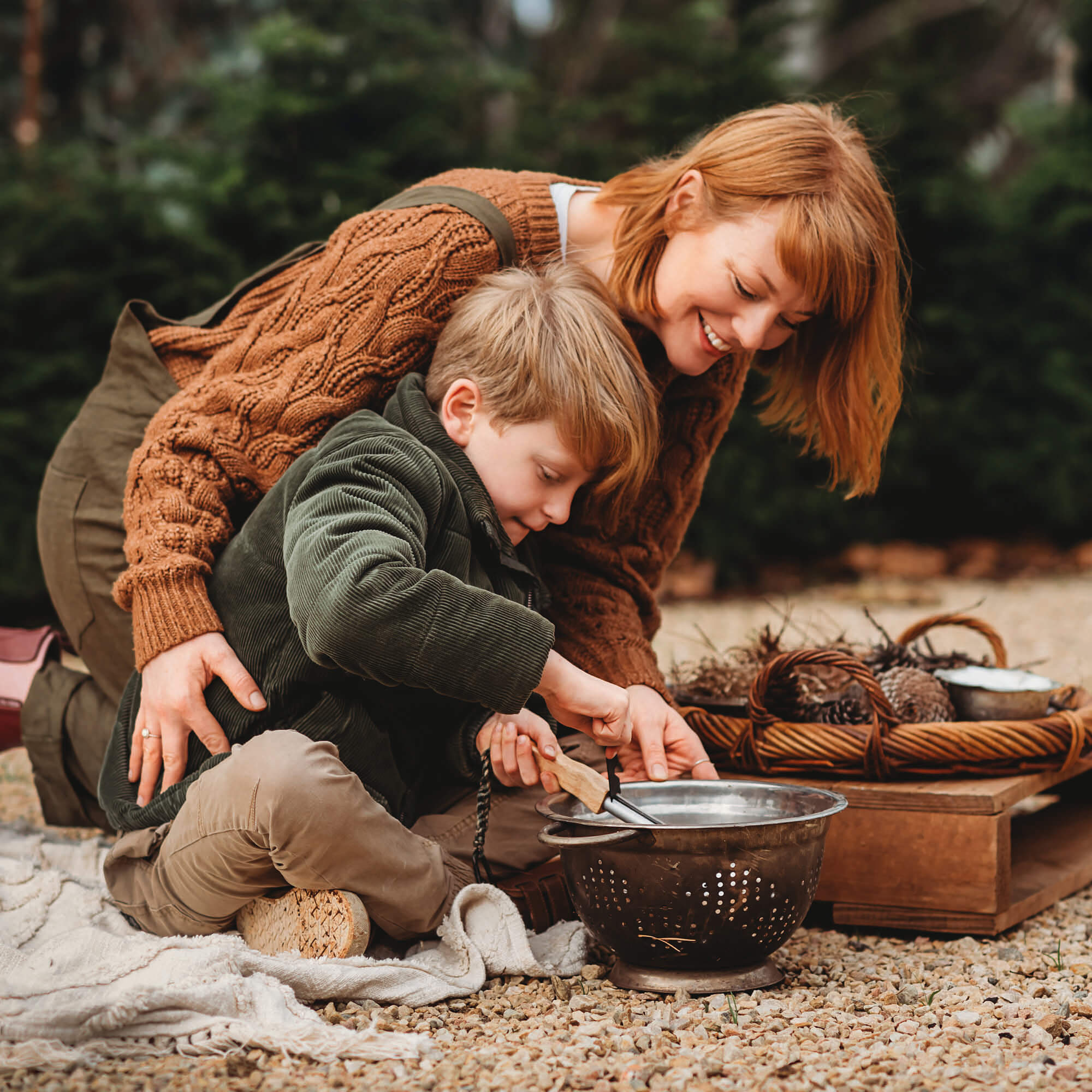 Boy and his Mum using flint and stone style fire starter with wooden handle with kindling made by Your Wild Books