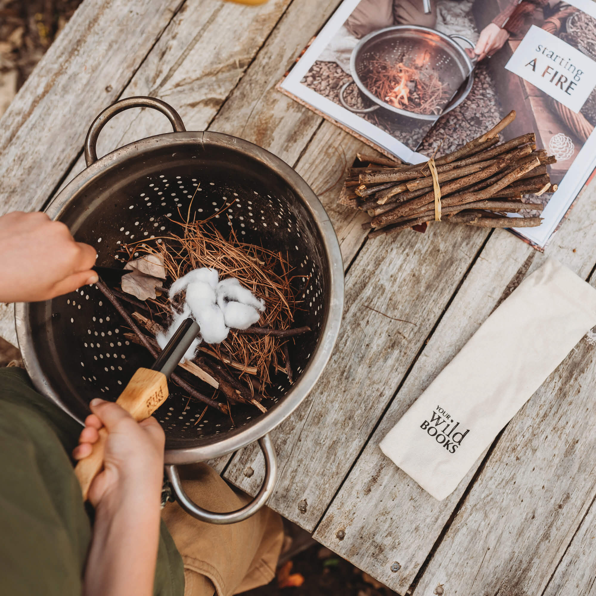 Boy using flint and stone style fire starter with wooden handle with kindling made by Your Wild Books