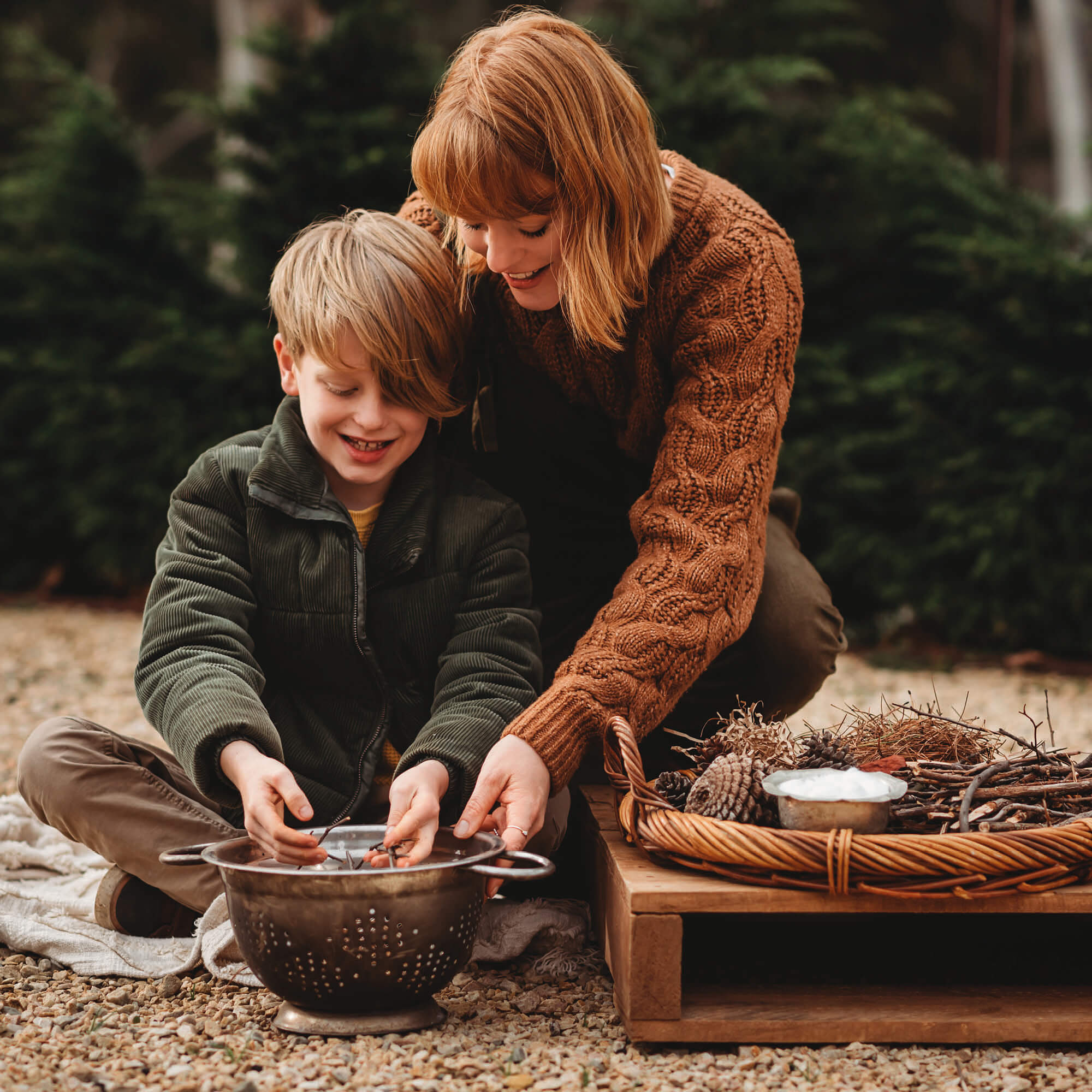 Boy and Mum using flint and stone style fire starter with wooden handle with kindling made by Your Wild Books