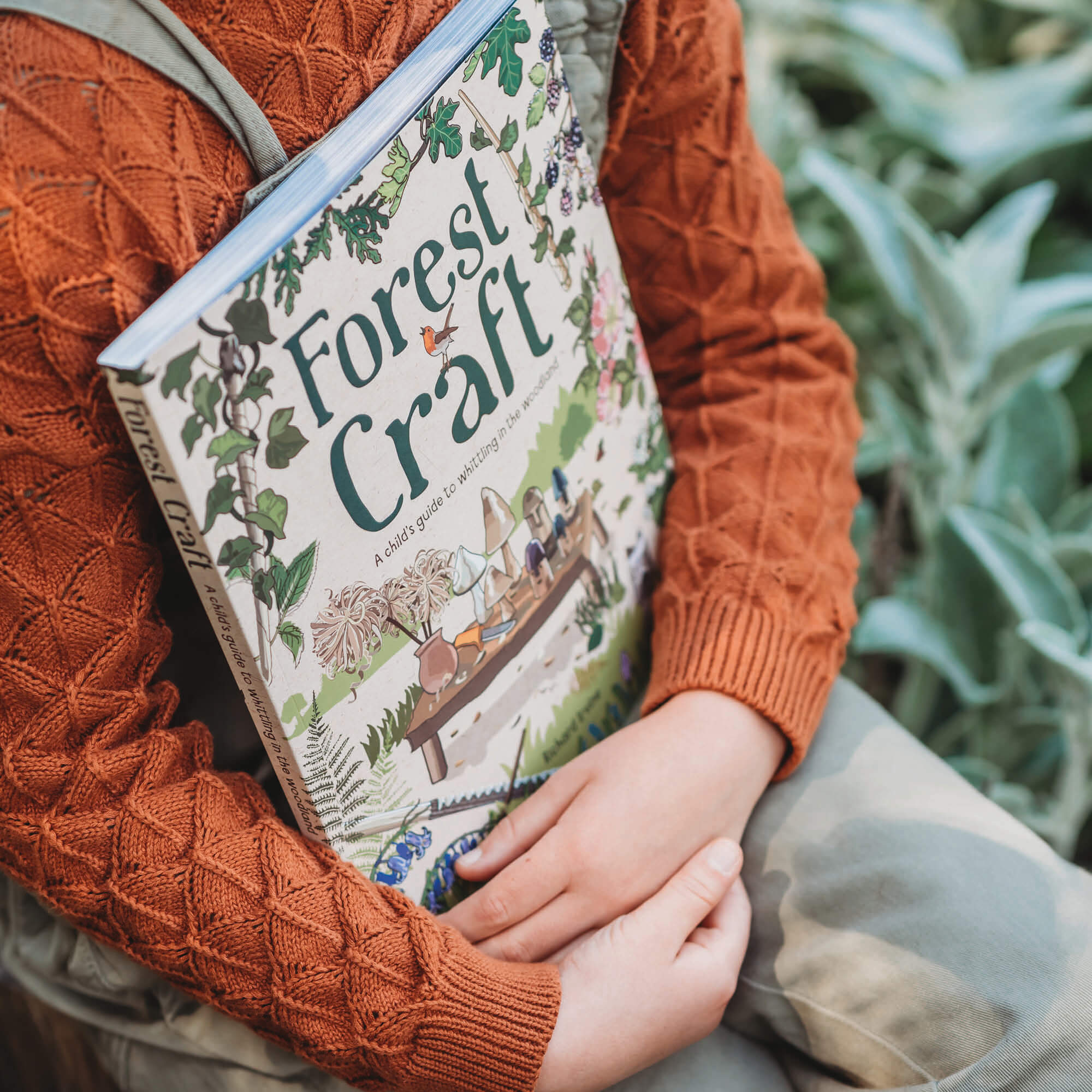 Child in nature holding Book Forest Craft, a child&