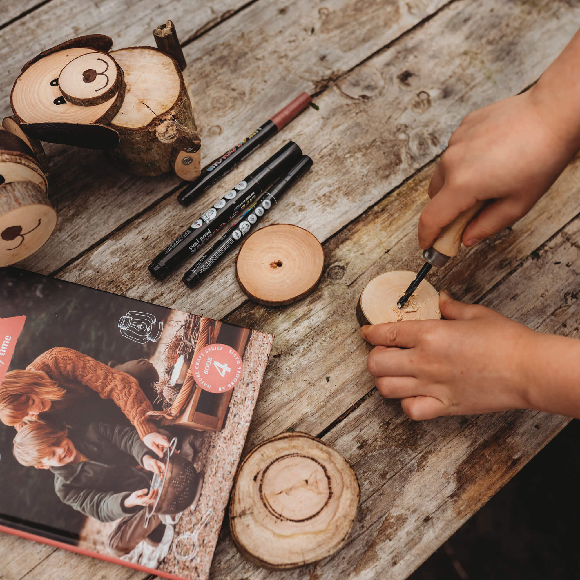 Drilling into a small piece of wood with a kid size hand drill with wooden handle and hessian style bag great for nature craft and woodworking projects from Your Wild Books