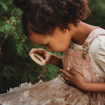 Girl holding Kikkerland dual magnifier wooden magnifying glass with two lenses for exploring nature and play  from Your Wild Books