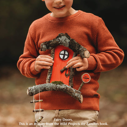 Boy holding red fairy door nature craft activity from Your Wild Books that has been decorated with brush tip and fine tip paint pens from Life of Colour