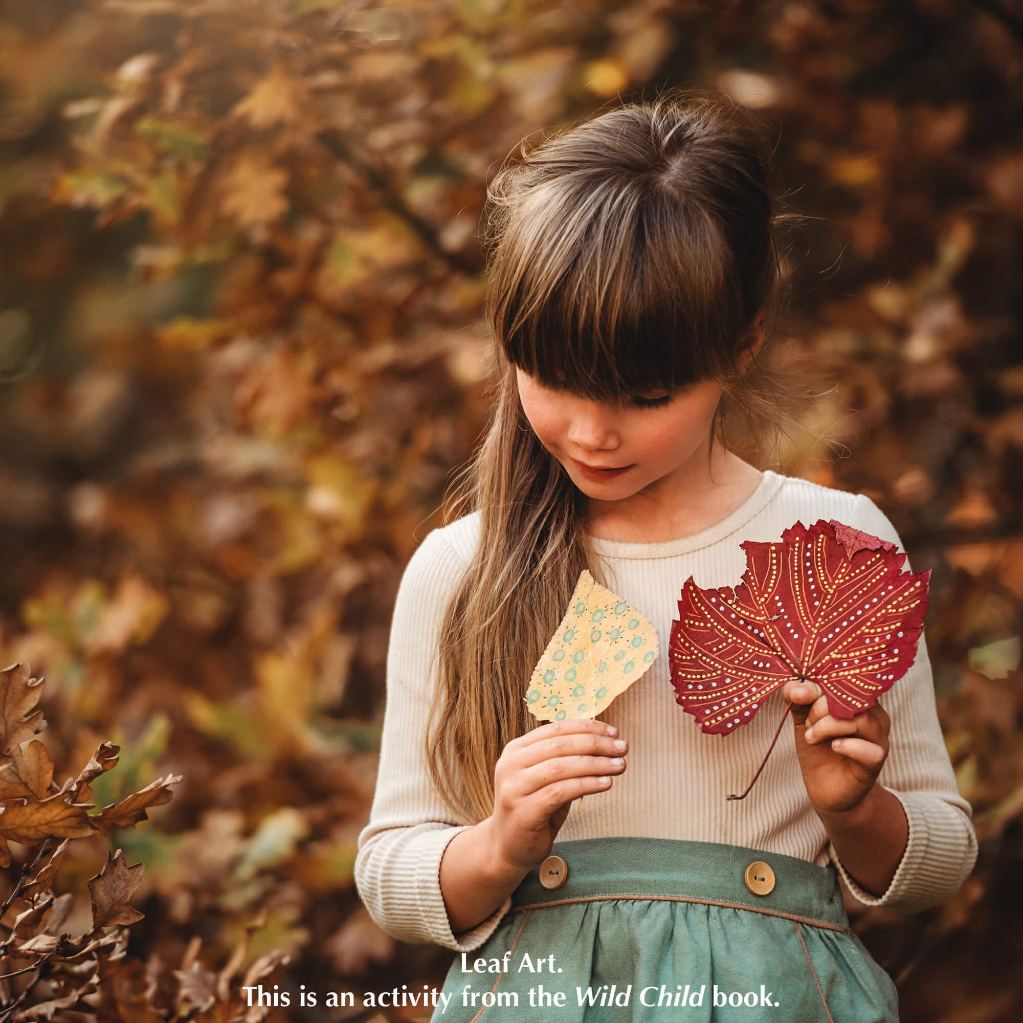 Child holding leaves from nature craft activity from Your Wild Books that have been decorated with paint pens from Life of Colour