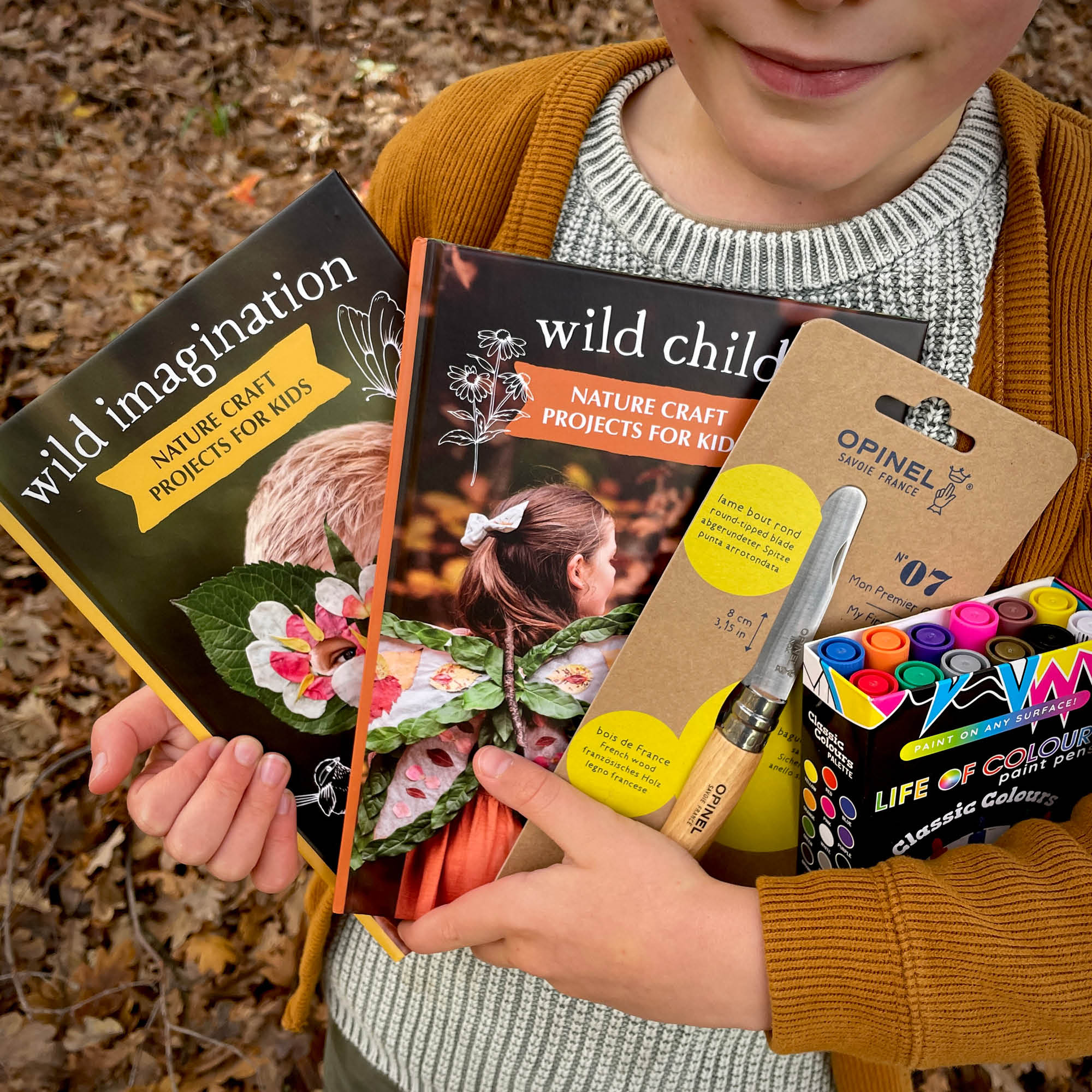 Child holding Nature Craft Starter Pack from Your Wild Books includes Wild Imagination book, Wild Child book, paint pens in classic colours and an opinel beginners whittling knife. Save 20%