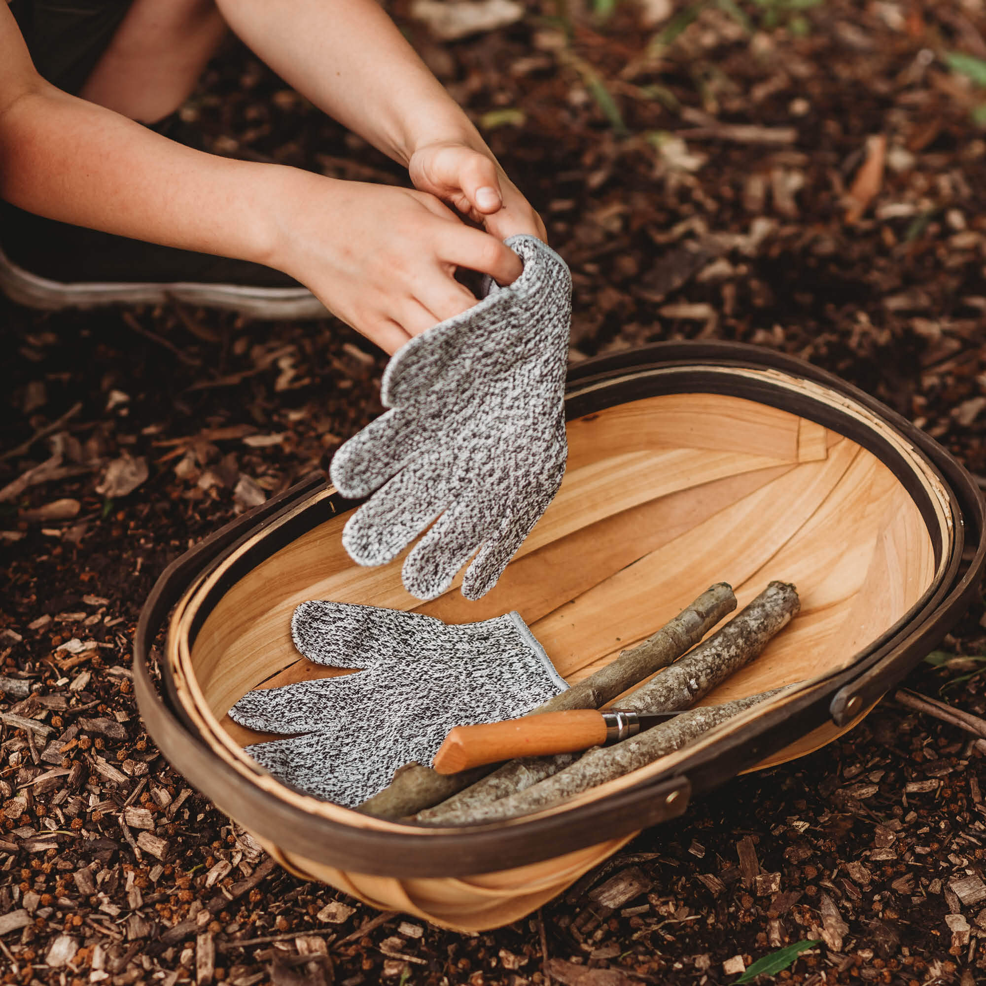 Child wearing cut resistant gloves for kids when doing wood whittling and using other tools for nature craft, from Your Wild Books. Level 5 HPPE protection.