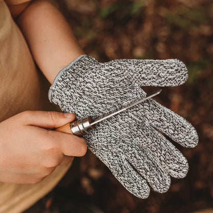 Child wearing cut resistant gloves for kids when doing wood whittling and using other tools for nature craft, from Your Wild Books. Level 5 HPPE protection.