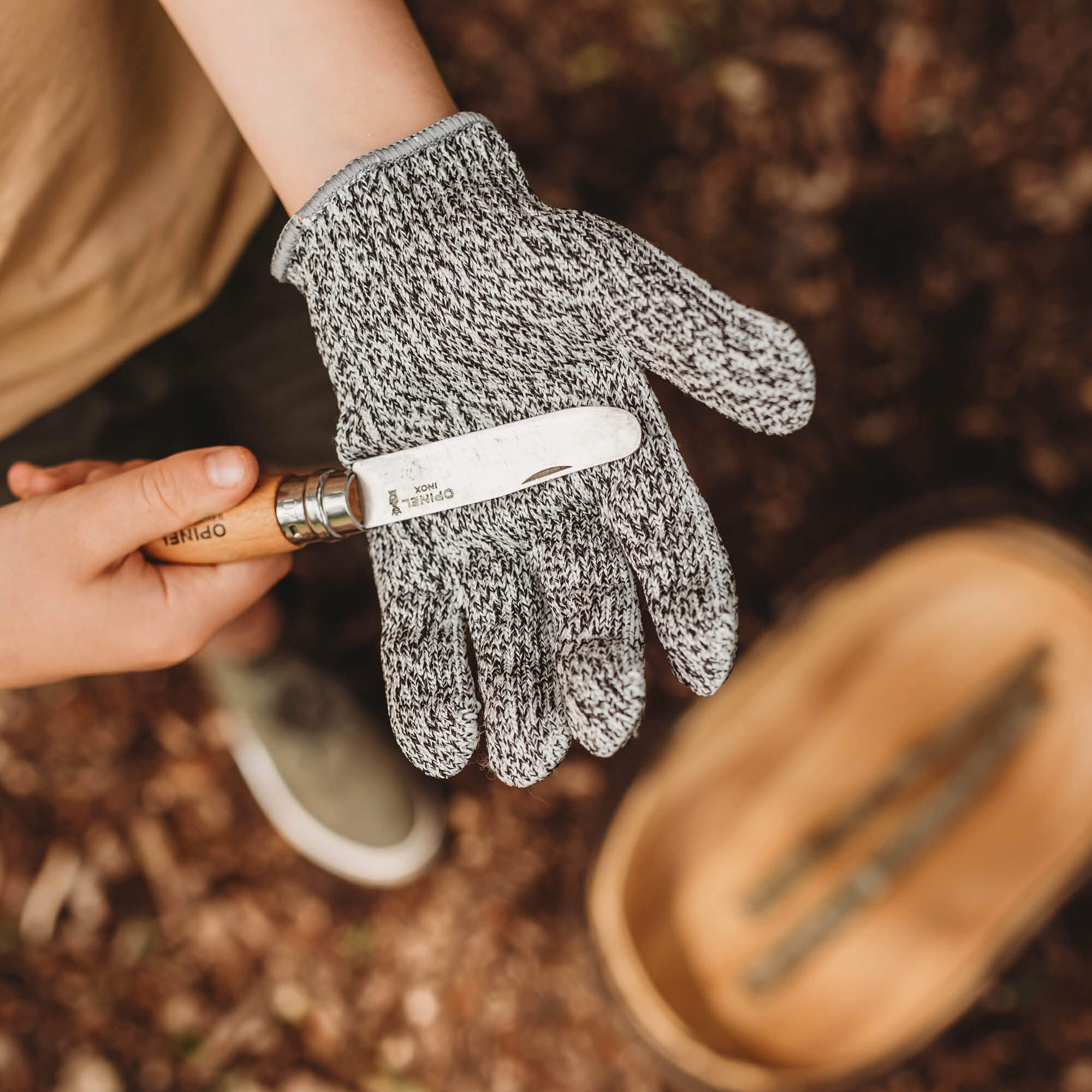 Child wearing cut resistant gloves for kids when doing wood whittling and using other tools for nature craft, from Your Wild Books. Level 5 HPPE protection.