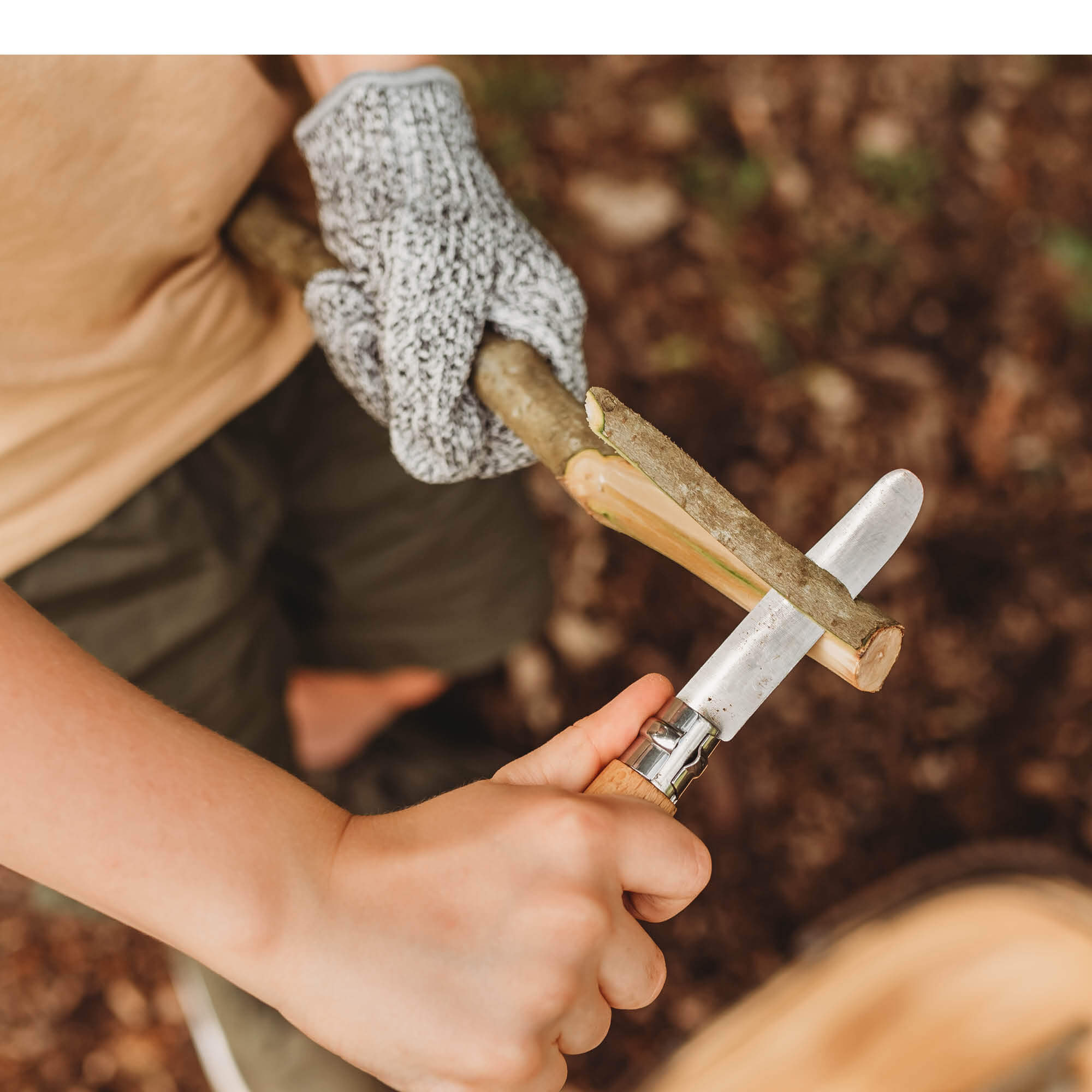 Child wearing cut resistant gloves for kids when doing wood whittling and using other tools for nature craft, from Your Wild Books. Level 5 HPPE protection.