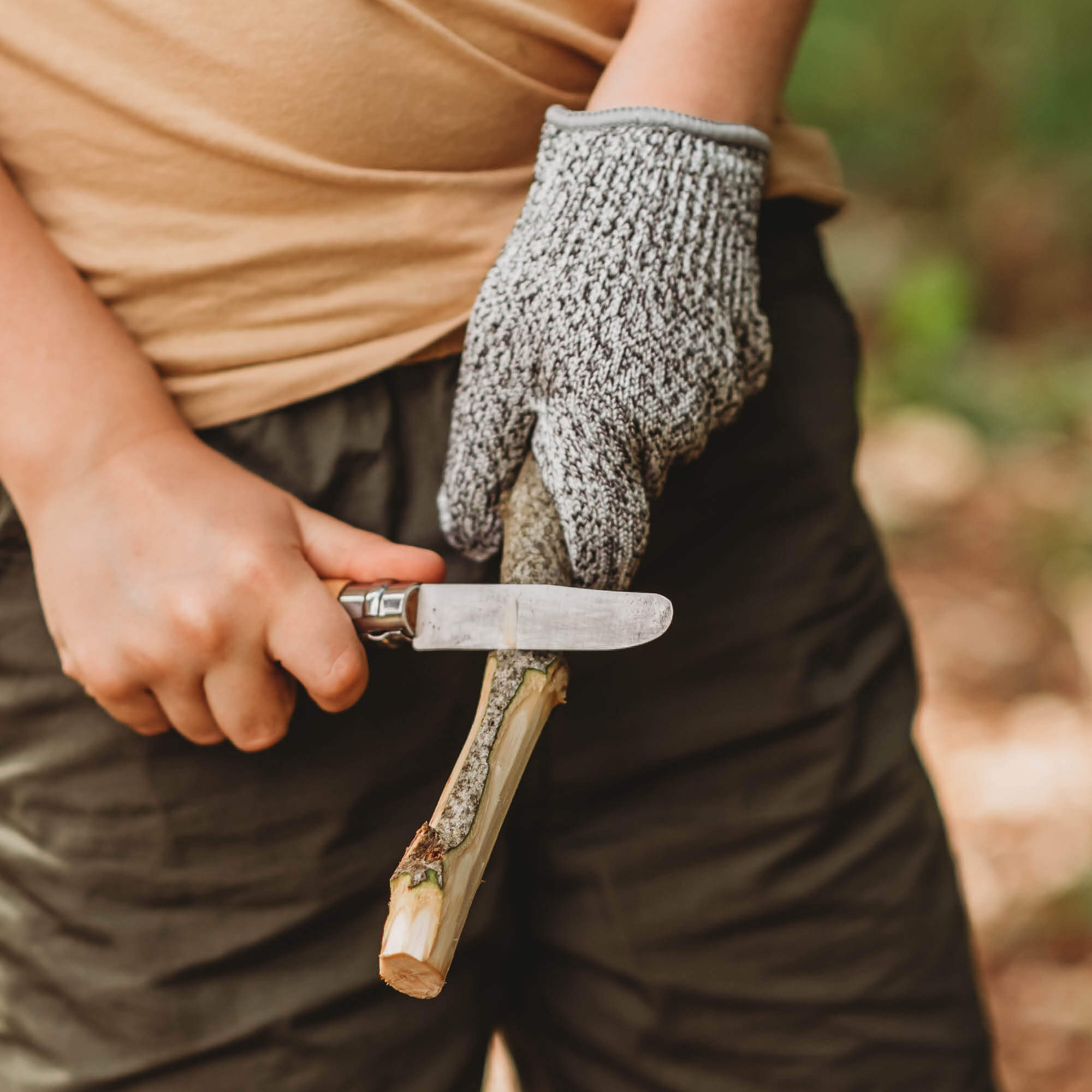 Child wearing cut resistant gloves for kids when doing wood whittling and using other tools for nature craft, from Your Wild Books. Level 5 HPPE protection.