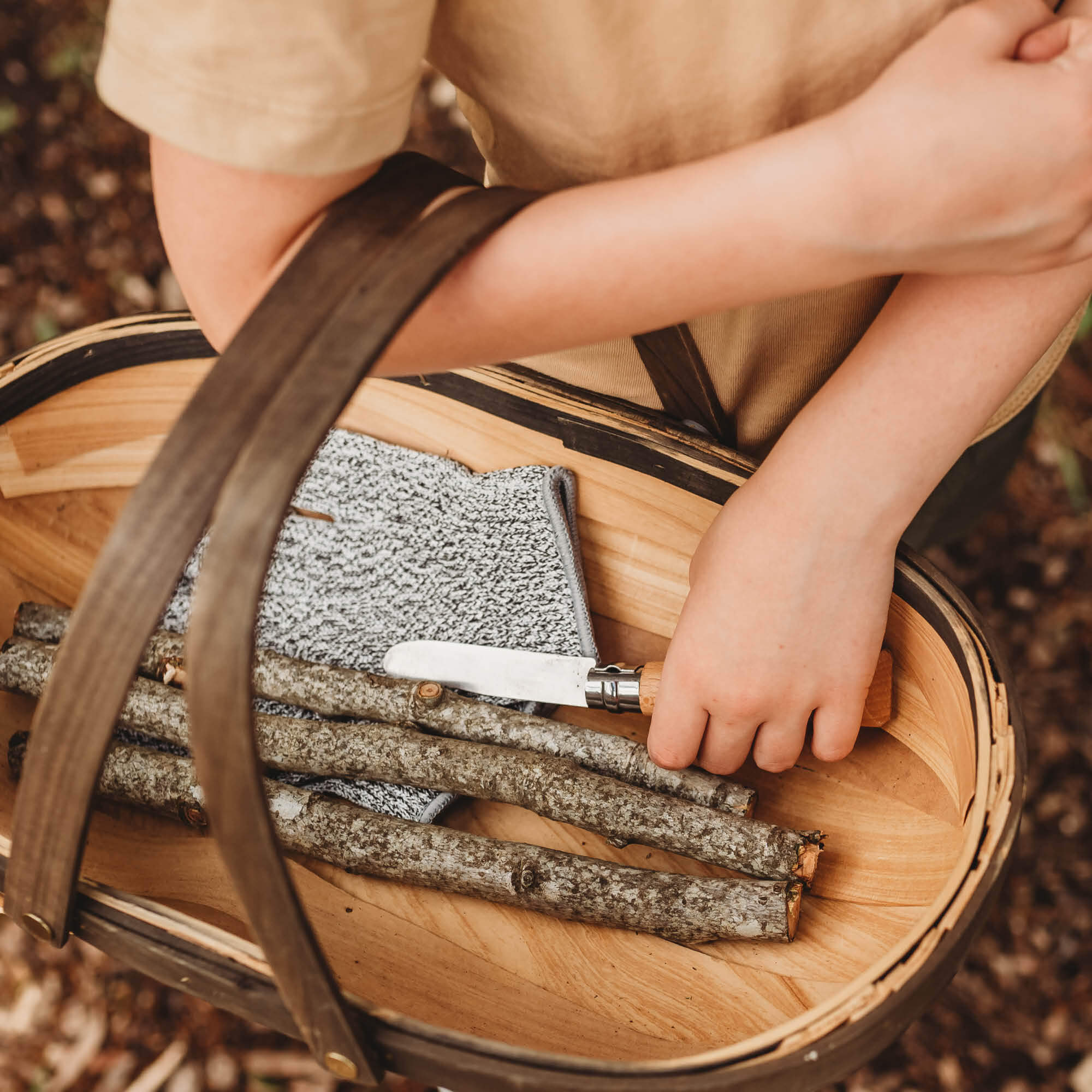 Child wearing cut resistant gloves for kids when doing wood whittling and using other tools for nature craft, from Your Wild Books. Level 5 HPPE protection.