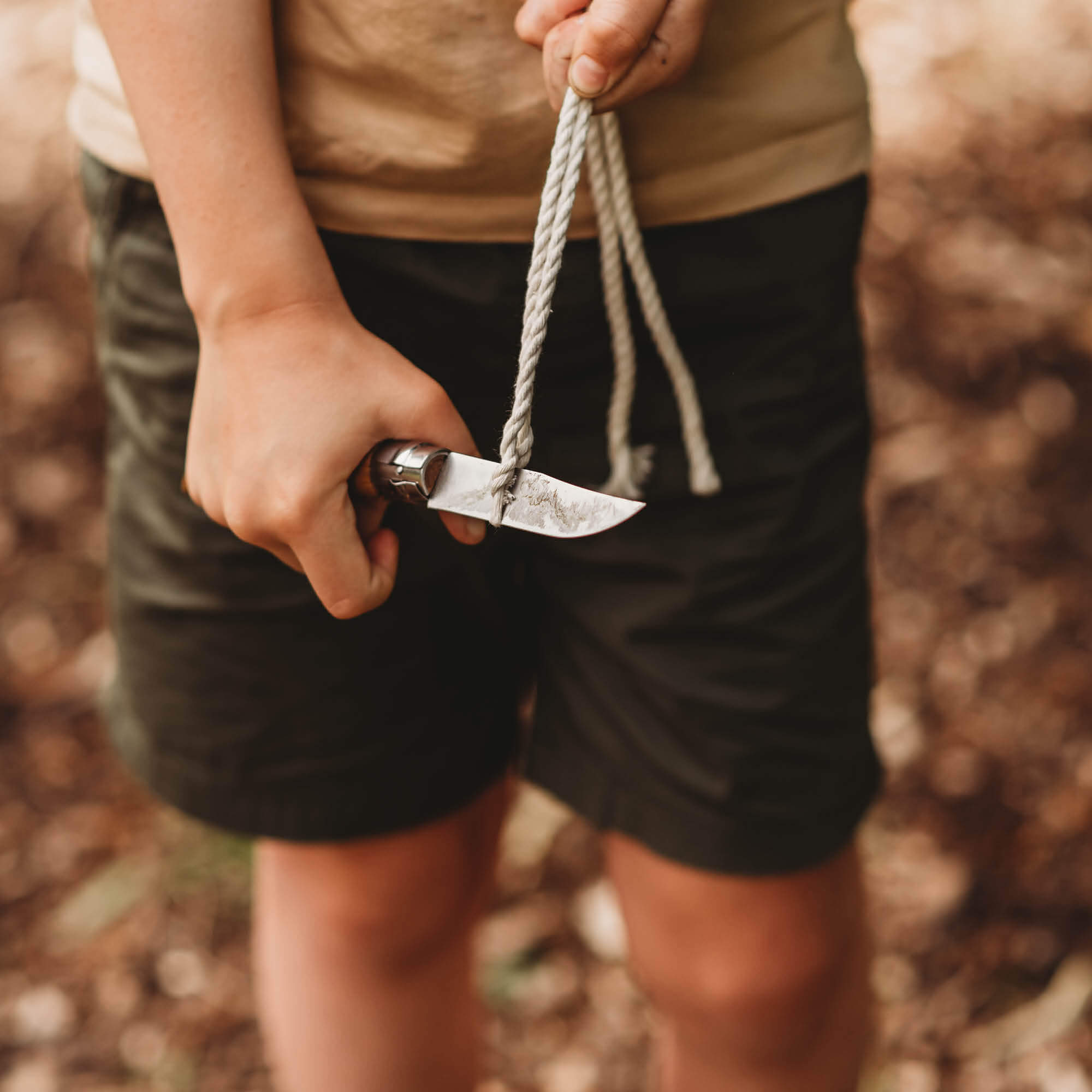 Child cutting rope with advanced whittling knife. Wood whittling knives for kids for all your nature craft projects, suitable for beginners and advanced woodworkers. Made by Opinel from Your Wild Books.