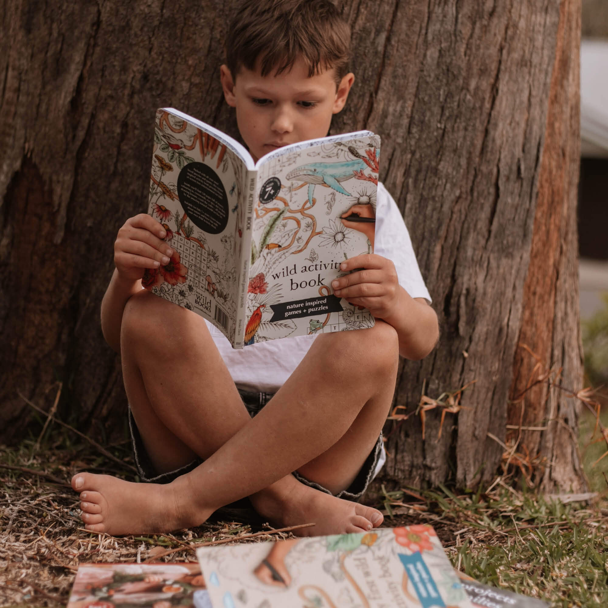 Child reading Wild Activity Book, nature inspired games and puzzles by Your Wild Books. Made in Australia for kids over 7 years.