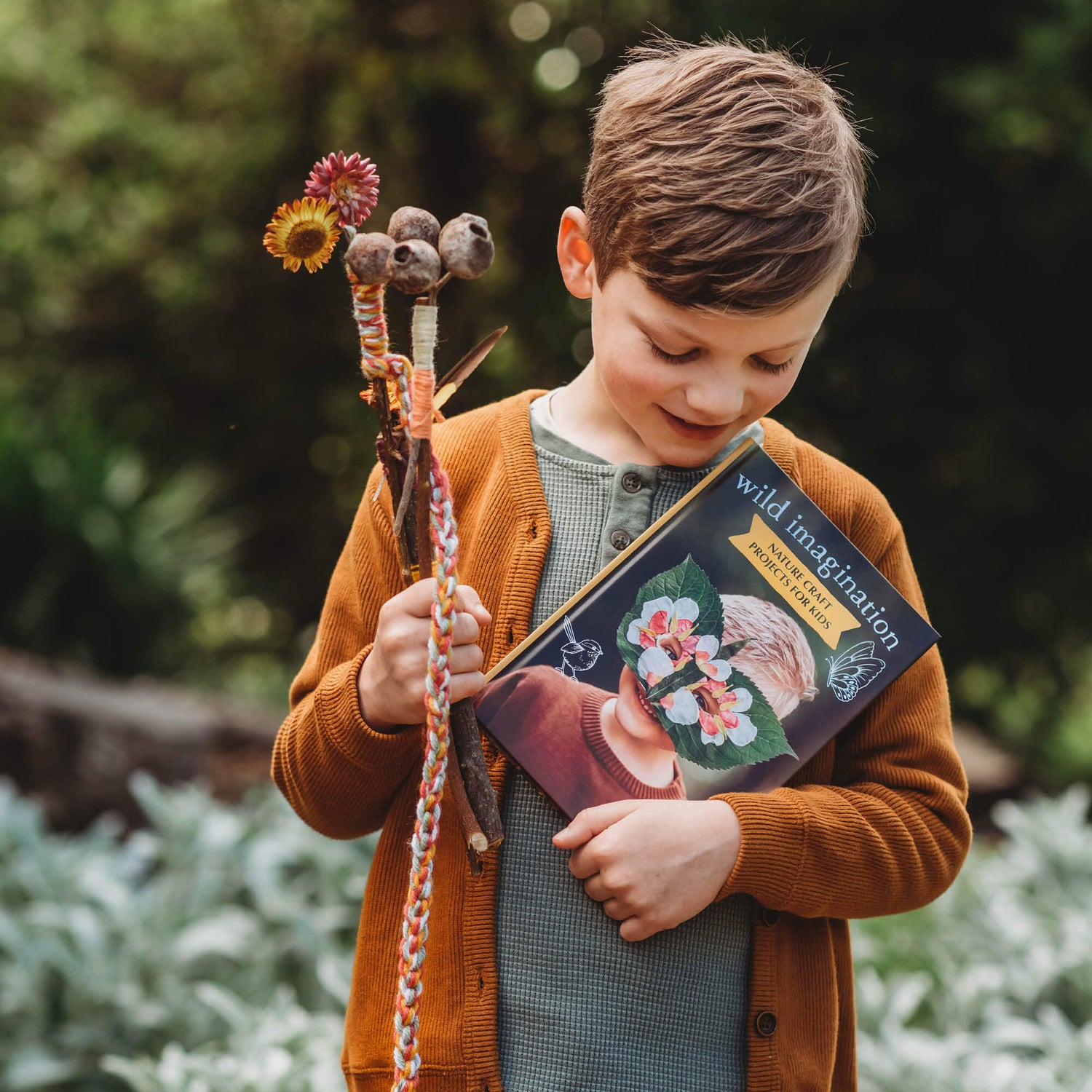 Boy holding magic wands made from nature and Wild Imagination, nature craft projects for kids book, made in Australia by Your Wild Books. 