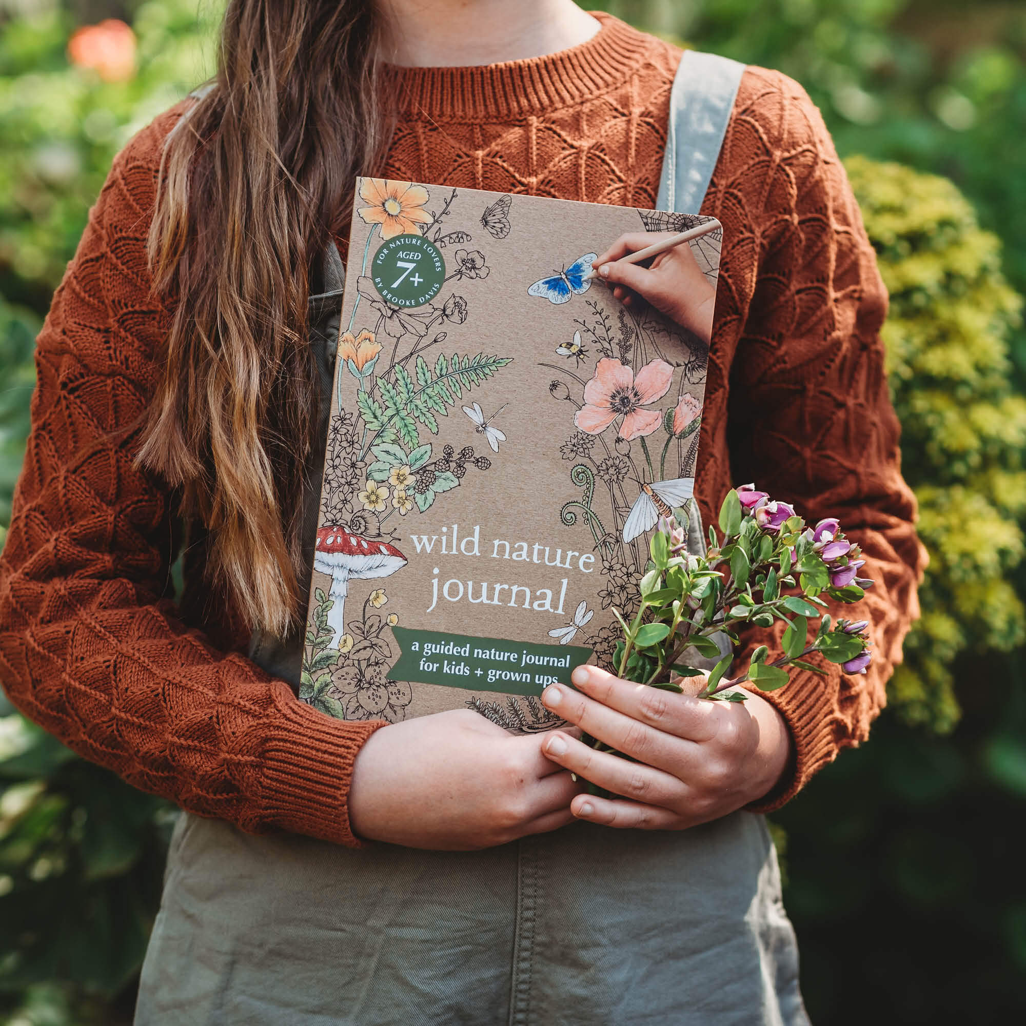 Child holding flowers and Wild Nature Journal, a guided nature journal for kids and grown ups is made in Australia by Your Wild Books.