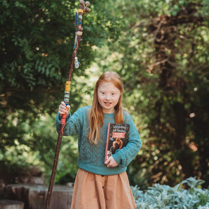 Child holding a decorated hiking stick they made using instructions from Wild Projects for Families book has fun adventures and DIY activities for family outdoor time, is made in Australia by Your Wild Books.