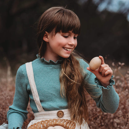 Girl holding large wooden egg for craft sugar free alternative to Easter eggs made by Your Wild Books