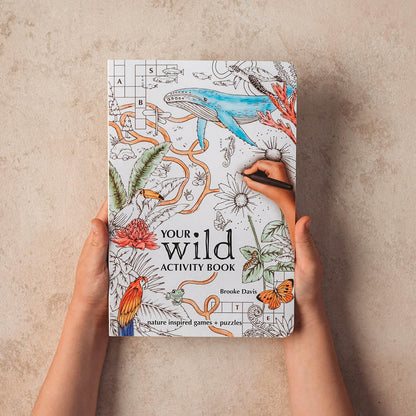 Child hands holding Your Wild Activity Book, nature inspired games and puzzles, made in Australia by Your Wild Books.