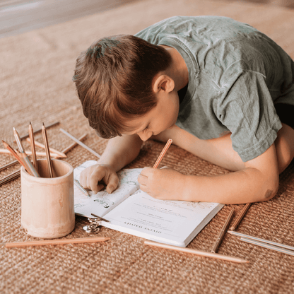 Boy sitting on floor doing activity from Your Wild Activity Book, nature inspired games and puzzles, made in Australia by Your Wild Books.
